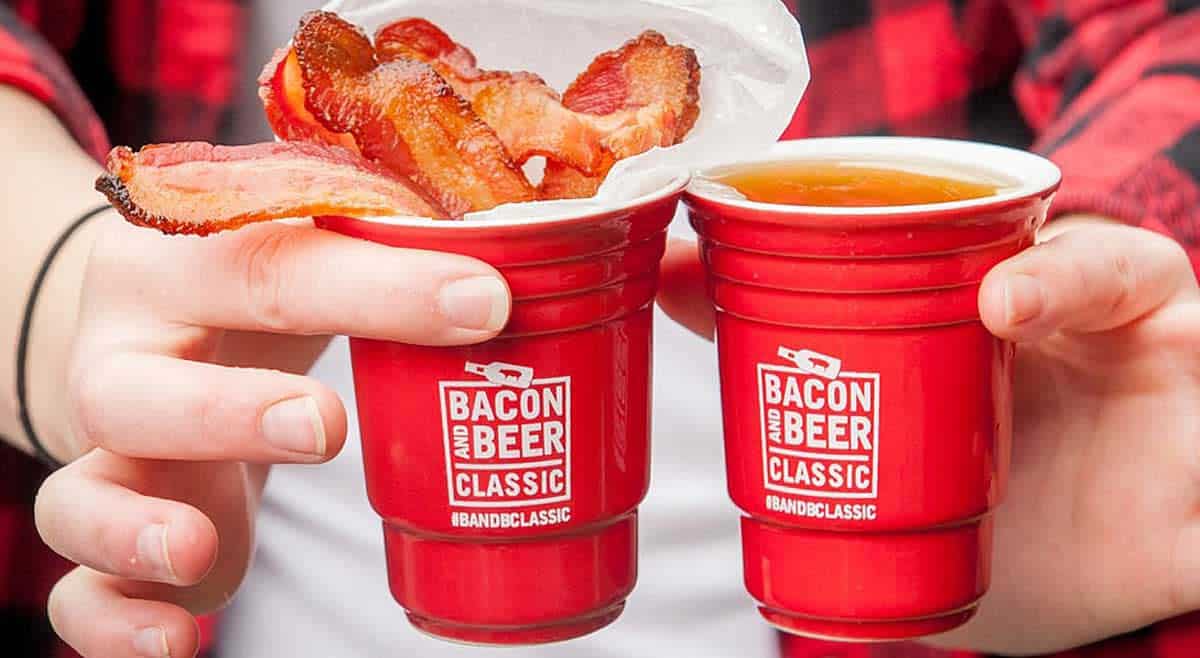 two hands holding red beer cups that say Bacon and Beer Classic