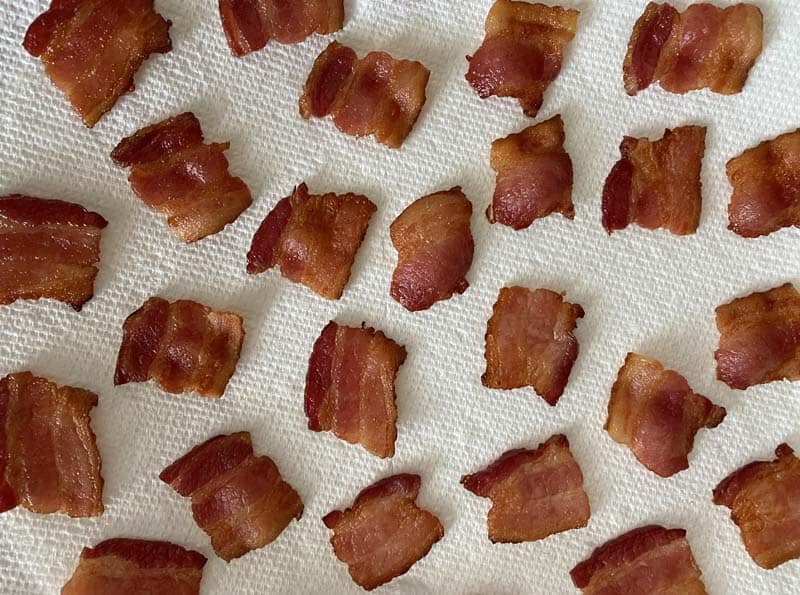 Square pieces of bacon cooling on a paper towel
